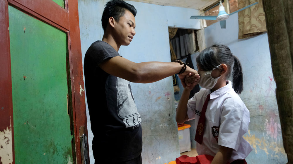 <p>Keysha (8) menyalami ayahnya sebelum berangkat mengikuti pelajaran secara online di gerai ayam krispy tempat ibunya bekerja, di Jalan Bukit Duri Tanjakan, Gang Langgar, Jakarta Selatan, Selasa, 28 Juli 2020. Anak pertama dari tiga bersaudara pasangan Firman (32) dan Okta (31) tampak tekun mengikuti pelajaran berbasis online di masa kernormalan baru saat ini. Keluarga yang terdampak secara ekonomi akibat  ayahnya yang dirumahkan dari pekerjaan, membuat ibunya harus turun tangan dengan bekerja di gerai ayam krispy milik tetangga mereka. Belum lagi sistem sekolah online yang memaksa orang tua Keysha harus menyisihkan penghasilan untuk membeli pulsa Rp 25000 per minggu agar anak mereka dapat terus belajar. Ditengah himpitan ekonomi, Keysha yang bercita-cita menjadi seorang dokter ini terus memupuk semangatnya untuk belajar agar bisa membanggakan keluarga, sembari berdoa agar ayahnya kembali mendapatkan pekerjaan dan badai corona segera berakhir. Foto: Ismail Pohan/TrenAsia</p>
