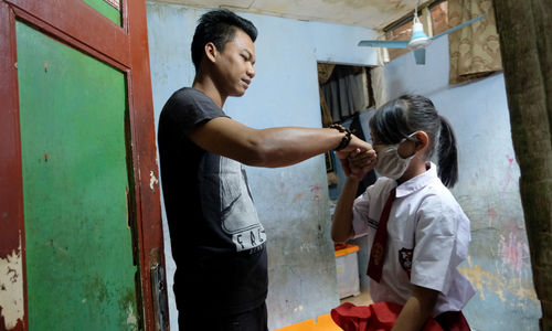 <p>Keysha (8) menyalami ayahnya sebelum berangkat mengikuti pelajaran secara online di gerai ayam krispy tempat ibunya bekerja, di Jalan Bukit Duri Tanjakan, Gang Langgar, Jakarta Selatan, Selasa, 28 Juli 2020. Anak pertama dari tiga bersaudara pasangan Firman (32) dan Okta (31) tampak tekun mengikuti pelajaran berbasis online di masa kernormalan baru saat ini. Keluarga yang terdampak secara ekonomi akibat  ayahnya yang dirumahkan dari pekerjaan, membuat ibunya harus turun tangan dengan bekerja di gerai ayam krispy milik tetangga mereka. Belum lagi sistem sekolah online yang memaksa orang tua Keysha harus menyisihkan penghasilan untuk membeli pulsa Rp 25000 per minggu agar anak mereka dapat terus belajar. Ditengah himpitan ekonomi, Keysha yang bercita-cita menjadi seorang dokter ini terus memupuk semangatnya untuk belajar agar bisa membanggakan keluarga, sembari berdoa agar ayahnya kembali mendapatkan pekerjaan dan badai corona segera berakhir. Foto: Ismail Pohan/TrenAsia</p>
