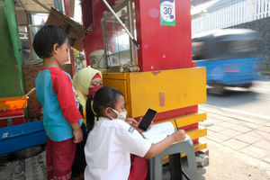 <p>Keysha (8) mengikuti pelajaran secara online di dampingi bunda bersama adiknya di gerai ayam krispy tempat ibunya bekerja, di Jalan Bukit Duri Tanjakan, Gang Langgar, Jakarta Selatan, Selasa, 28 Juli 2020. Anak pertama dari tiga bersaudara pasangan Firman (32) dan Okta (31) tampak tekun mengikuti pelajaran berbasis online di masa kernormalan baru saat ini. Keluarga yang terdampak secara ekonomi akibat ayahnya yang dirumahkan dari pekerjaan, membuat ibunya harus turun tangan dengan bekerja di gerai ayam krispy milik tetangga mereka. Belum lagi sistem sekolah online yang memaksa orang tua Keysha harus menyisihkan penghasilan untuk membeli pulsa Rp 25000 per minggu agar anak mereka dapat terus belajar. Ditengah himpitan ekonomi, Keysha yang bercita-cita menjadi seorang dokter ini terus memupuk semangatnya untuk belajar agar bisa membanggakan keluarga, sembari berdoa agar ayahnya kembali mendapatkan pekerjaan dan badai corona segera berakhir. Foto: Ismail Pohan/TrenAsia</p>