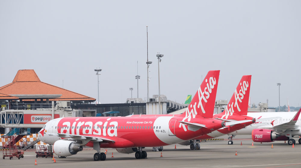 <p>Maskapai penerbangan komersil Air Asia tampak terparkir di Bandara Soekarno Hatta, Tangerang, Banten, Jum’at, 3 Juni 2020. PT Angkasa Pura II (Persero) akan mengkordinasikan permintaan maskapai untuk slot penerbangan, rute penerbangan dan frekuensi penerbangan di dalam satu rute agar kembali terciptanya keseimbangan terhadap tingkat permintaan dari penumpang, saat ini PT Angkasa Pura II mengaku slot terbang di Bandara Soekarno Hatta belum optimal dimanfaatkan oleh maskapai pada masa new normal ini. Foto: Ismail Pohan/TrenAsia</p>
