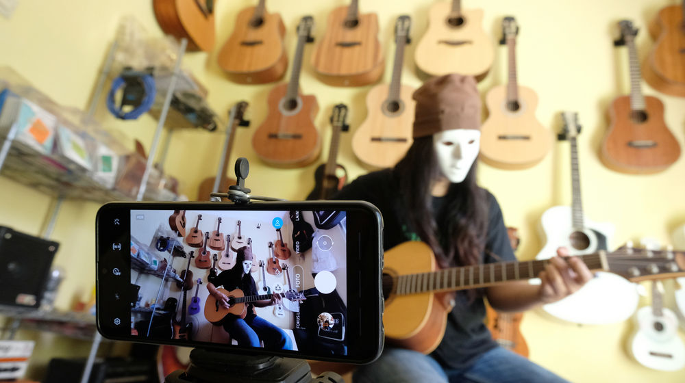 <p>Pemilik showroom dan bengkel Gitar “music666”, Ridwan mendemonstrasikan gitar yang akan dijual secara daring di  Ciledug, Tangerang, Banten, Rabu 22 Juli 2020. Kementerian Koordinator Bidang Kemaritiman dan Investasi terus mendorong 10 juta Usaha Mikro Kecil Menengah (UMKM) terhubung dengan platform digital atau “go online” hingga akhir tahun ini. Perubahan tren dan perilaku konsumen dengan membatasi interaksi fisik dan mengurangi aktivitas di luar rumah terbukti dapat memberi peluang lebih besar kepada UMKM yang sudah terhubung dengan ekosistem digital untuk bertahan atau bahkan melaju di tengah pandemi COVID-19. Foto: Ismail Pohan/TrenAsia</p>
