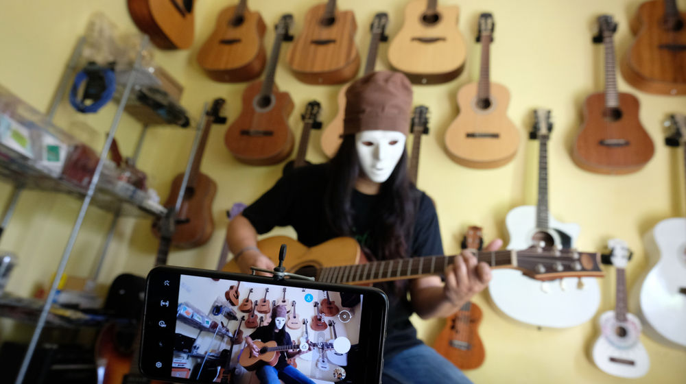 <p>Pemilik showroom dan bengkel Gitar “music666”, Ridwan mendemonstrasikan gitar yang akan dijual secara daring di Ciledug, Tangerang, Banten, Rabu 22 Juli 2020. Kementerian Koordinator Bidang Kemaritiman dan Investasi terus mendorong 10 juta Usaha Mikro Kecil Menengah (UMKM) terhubung dengan platform digital atau “go online” hingga akhir tahun ini. Perubahan tren dan perilaku konsumen dengan membatasi interaksi fisik dan mengurangi aktivitas di luar rumah terbukti dapat memberi peluang lebih besar kepada UMKM yang sudah terhubung dengan ekosistem digital untuk bertahan atau bahkan melaju di tengah pandemi COVID-19. Foto: Ismail Pohan/TrenAsia</p>