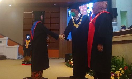 <p>Robot-robot wisudawan berjabat tangan dengan Rektor Undip Yos Johan Utama, seusai menerima ijazah. / Istimewa.</p>
