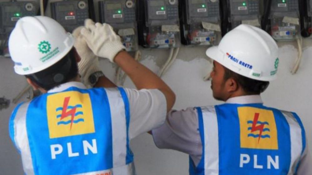 Petugas PLN sedang mencatat meteran listrik di rumah warga.