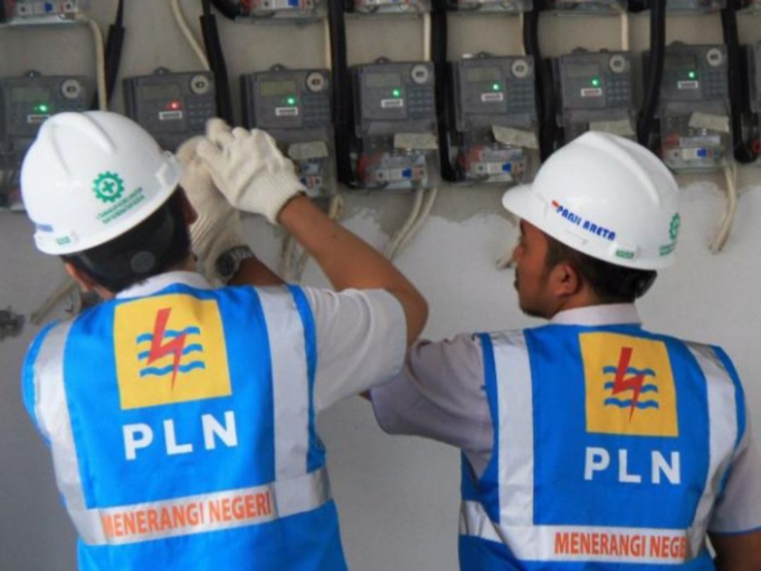 Petugas PLN sedang mencatat meteran listrik di rumah warga.