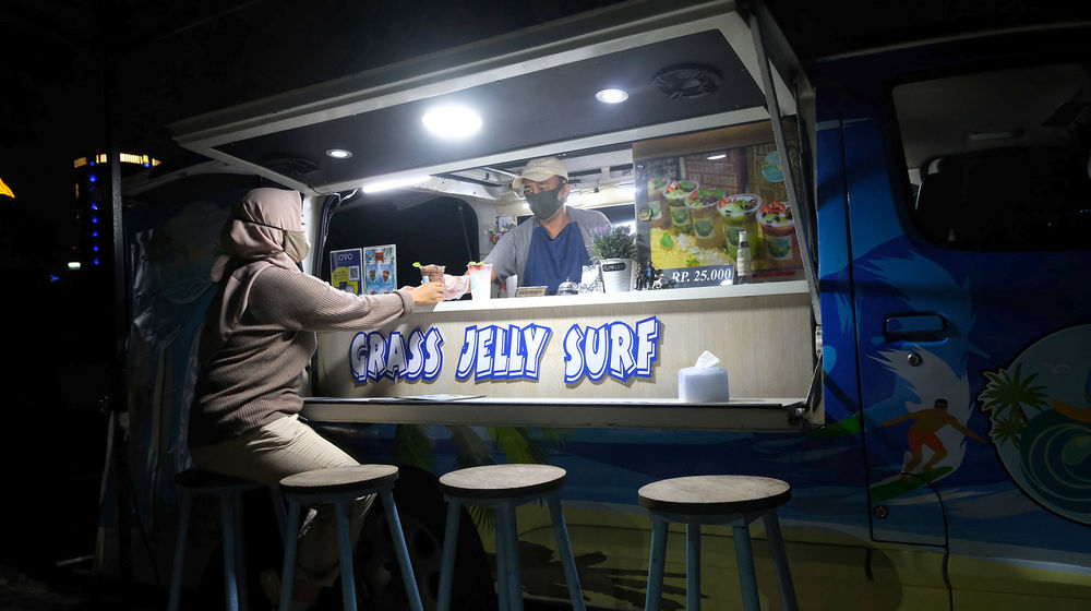 <p>Berni (47) bersama istrinya Arianti (36) berada di gerai foodtruck “Grass Jelly Surf” miliknya yang menjual minuman segar di area perkantoran Cibis Park, kawasan TB Simatupang, Jakarta Selatan, Kamis, 13 Agustus 2020. Bisnis yang sudah dirintis selama 6 tahun ini, masih berusaha bertahan ditengah hantaman pandemi. Sepinya event dan kegiatan komunitas foodtruck membuat Berni harus rela kehilangan omset yang selama ini diraup dari hasil usahanya yang termasuk dalam Usaha Mikro Kecil Menengah (UMKM) mitra binaan Pertamina tersebut. Pria yang berlatar belakang Chef di sebuah kapal pesiar selama 2 tahun ini, berharap pemerintah khususnya wadah binaan seperti Pertamina bisa memberikan perhatian khusus kepada pelaku UMKM yang terdampak pandemi Covid-19 untuk tetap hidup di bidang usahanya dengan bantuan yang nyata menyasar pada suplai produk yang mereka pasarkan. Karena selama ini mereka hanya gencar ditawarkan bantuan berupa pinjaman dana yang justru dianggap semakin menambah beban kedepannya. Foto: Ismail Pohan/TrenAsia</p>
