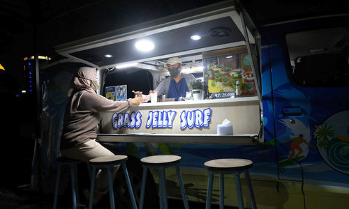<p>Berni (47) bersama istrinya Arianti (36) berada di gerai foodtruck &#8220;Grass Jelly Surf&#8221; miliknya yang menjual minuman segar di area perkantoran Cibis Park, kawasan TB Simatupang, Jakarta Selatan, Kamis, 13 Agustus 2020. Bisnis yang sudah dirintis selama 6 tahun ini, masih berusaha bertahan ditengah hantaman pandemi. Sepinya event dan kegiatan komunitas foodtruck membuat Berni harus rela kehilangan omset yang selama ini diraup dari hasil usahanya yang termasuk dalam Usaha Mikro Kecil Menengah (UMKM) mitra binaan Pertamina tersebut. Pria yang berlatar belakang Chef di sebuah kapal pesiar selama 2 tahun ini, berharap pemerintah khususnya wadah binaan seperti Pertamina bisa memberikan perhatian khusus kepada pelaku UMKM yang terdampak pandemi Covid-19 untuk tetap hidup di bidang usahanya dengan bantuan yang nyata menyasar pada suplai produk yang mereka pasarkan. Karena selama ini mereka hanya gencar ditawarkan bantuan berupa pinjaman dana yang justru dianggap semakin menambah beban kedepannya. Foto: Ismail Pohan/TrenAsia</p>
