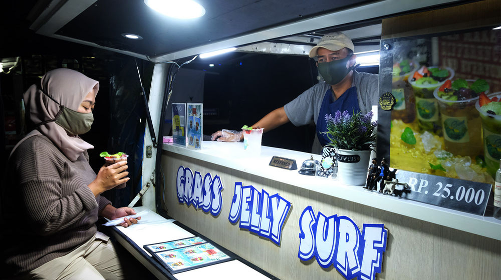 <p>Berni (47) bersama istrinya Arianti (36) berada di gerai foodtruck “Grass Jelly Surf” miliknya yang menjual minuman segar di area perkantoran Cibis Park, kawasan TB Simatupang, Jakarta Selatan, Kamis, 13 Agustus 2020. Bisnis yang sudah dirintis selama 6 tahun ini, masih berusaha bertahan ditengah hantaman pandemi. Sepinya event dan kegiatan komunitas foodtruck membuat Berni harus rela kehilangan omset yang selama ini diraup dari hasil usahanya yang termasuk dalam Usaha Mikro Kecil Menengah (UMKM) mitra binaan Pertamina tersebut. Pria yang berlatar belakang Chef di sebuah kapal pesiar selama 2 tahun ini, berharap pemerintah khususnya wadah binaan seperti Pertamina bisa memberikan perhatian khusus kepada pelaku UMKM yang terdampak pandemi Covid-19 untuk tetap hidup di bidang usahanya dengan bantuan yang nyata menyasar pada suplai produk yang mereka pasarkan. Karena selama ini mereka hanya gencar ditawarkan bantuan berupa pinjaman dana yang justru dianggap semakin menambah beban kedepannya. Foto: Ismail Pohan/TrenAsia</p>
