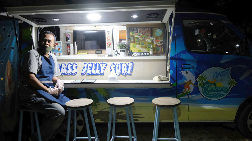 <p>Berni (47) berpose didepan gerai foodtruck “Grass Jelly Surf” miliknya yang menjual minuman segar di area perkantoran Cibis Park, kawasan TB Simatupang, Jakarta Selatan, Kamis, 13 Agustus 2020. Bisnis yang sudah dirintis selama 6 tahun ini, masih berusaha bertahan ditengah hantaman pandemi. Sepinya event dan kegiatan komunitas foodtruck membuat Berni harus rela kehilangan omset yang selama ini diraup dari hasil usahanya yang termasuk dalam Usaha Mikro Kecil Menengah (UMKM) mitra binaan Pertamina tersebut. Pria yang berlatar belakang Chef di sebuah kapal pesiar selama 2 tahun ini, berharap pemerintah khususnya wadah binaan seperti Pertamina bisa memberikan perhatian khusus kepada pelaku UMKM yang terdampak pandemi Covid-19 untuk tetap hidup di bidang usahanya dengan bantuan yang nyata menyasar pada suplai produk yang mereka pasarkan. Karena selama ini mereka hanya gencar ditawarkan bantuan berupa pinjaman dana yang justru dianggap semakin menambah beban kedepannya. Foto: Ismail Pohan/TrenAsia</p>
