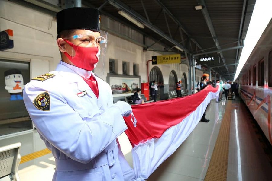 <p>Karyawan PT Kereta Api Indonesia (Persero) membentangkan bendera merah putih saat peringatan HUT ke-75 RI di stasiun. / Facebook @keretaapikita</p>

