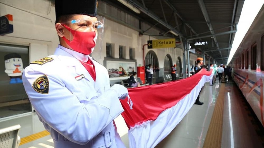 <p>Karyawan PT Kereta Api Indonesia (Persero) membentangkan bendera merah putih saat peringatan HUT ke-75 RI di stasiun. / Facebook @keretaapikita</p>
