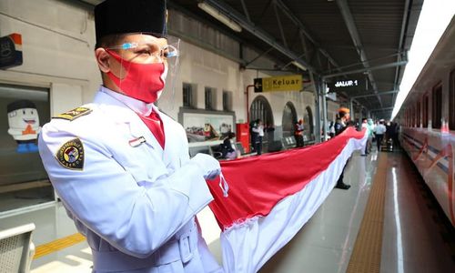 <p>Karyawan PT Kereta Api Indonesia (Persero) membentangkan bendera merah putih saat peringatan HUT ke-75 RI di stasiun. / Facebook @keretaapikita</p>
