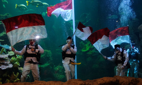 <p>Sejumlah penyelam mengibarkan Bendera Merah Putih saat upacara pengibaran Bendera Peringatan HUT ke-75 RI di Akuarium Utama Sea Word, Ancol, Jakarta, Senin, 17 Agustus 2020. Pengibaran Bendera Merah Putih dan Pembacaan Teks Proklamasi oleh empat orang penyelam profesional Sea Word Ancol tersebut berlangsung hikmat untuk memperingati Hari Kemerdekaan RI. Foto: Ismail Pohan/TrenAsia</p>
