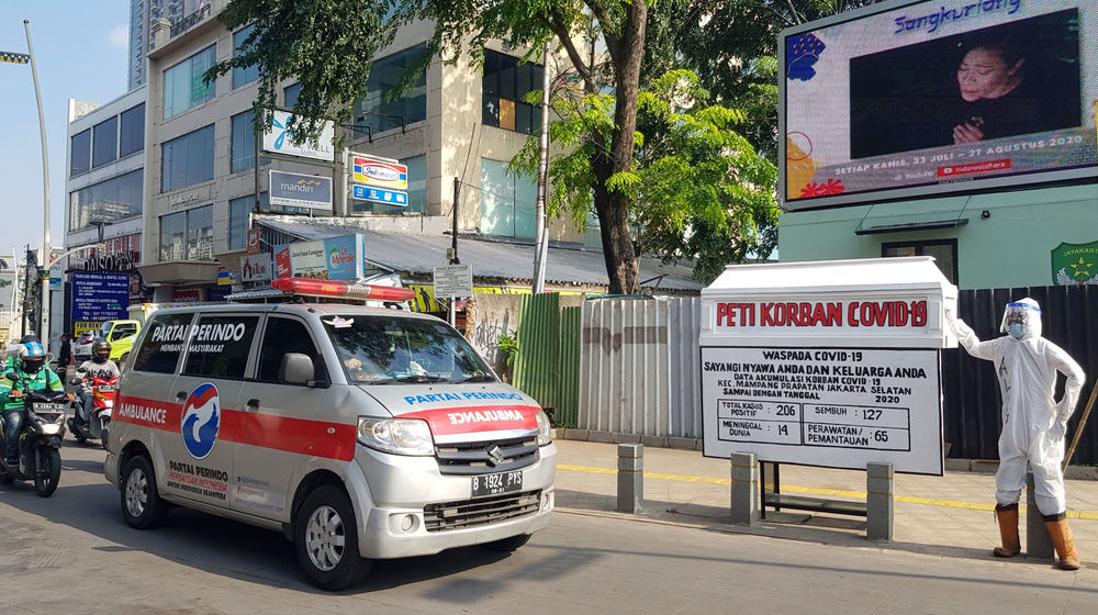 <p>Mobil ambulance melintas di dekat Tugu peti jenazah korban Covid-19 dan medis mengenakan hazmat terpajang di pertigaan Jalan Kemang 1, Jakarta Selatan, Sabtu, 15 Agustus 2020. Tugu tersebut dipajang untuk memberikan peringatan kepada warga untuk tetap waspada terhadap penyebaran Covid-19 yang masih menunjukkan statistik peningkatan korban setiap harinya. Foto: Ismail Pohan/TrenAsia</p>
