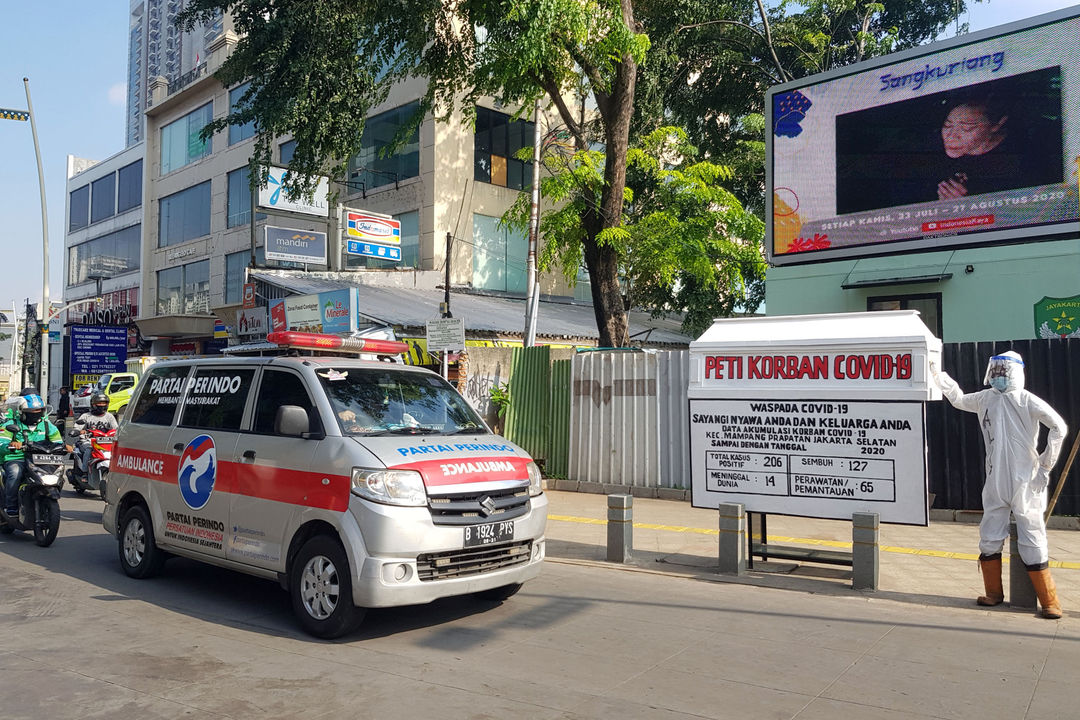 <p>Mobil ambulance melintas di dekat Tugu peti jenazah korban Covid-19 dan medis mengenakan hazmat terpajang di pertigaan Jalan Kemang 1, Jakarta Selatan, Sabtu, 15 Agustus 2020. Tugu tersebut dipajang untuk memberikan peringatan kepada warga untuk tetap waspada terhadap penyebaran Covid-19 yang masih menunjukkan statistik peningkatan korban setiap harinya. Foto: Ismail Pohan/TrenAsia</p>
