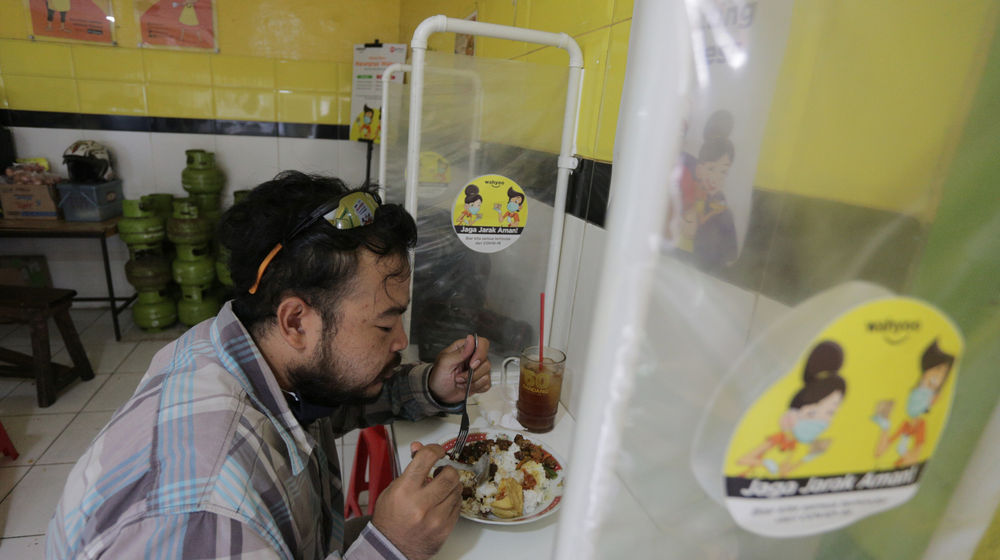 <p>Pelanggan menyantap makanan dengan suasana pembatasan jarak fisik di Warung Tegal (Warteg) Ellya, Cilandak Timur, Jakarta Selatan, Rabu, 5 Agustus 2020. Pemilik warteg mengaku tetap konsisten menerapkan protokol kesehatan pencegahan penyebaran Covid-19 sejak dimulainya masa PSBB transisi hingga saat ini, untuk memastikan keamanan pelanggan yang datang dengan mewajibkan penggunaan masker, menyediakan area cuci tangan, dan pembatasan jarak fisik di area warung tersebut. Foto: Ismail Pohan/TrenAsia</p>
