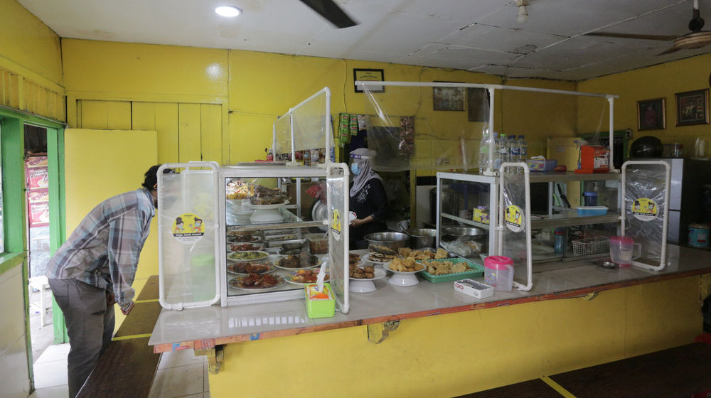 <p>Penjual menggunakan masker dan faceshield saat melayani pelanggan di Warung Tegal (Warteg) Ellya, Cilandak Timur, Jakarta Selatan, Rabu, 5 Agustus 2020. Pemilik warteg mengaku tetap konsisten menerapkan protokol kesehatan pencegahan penyebaran Covid-19 sejak dimulainya masa PSBB transisi hingga saat ini, untuk memastikan keamanan pelanggan yang datang dengan mewajibkan penggunaan masker, menyediakan area cuci tangan, dan pembatasan jarak fisik di area warung tersebut. Foto: Ismail Pohan/TrenAsia</p>