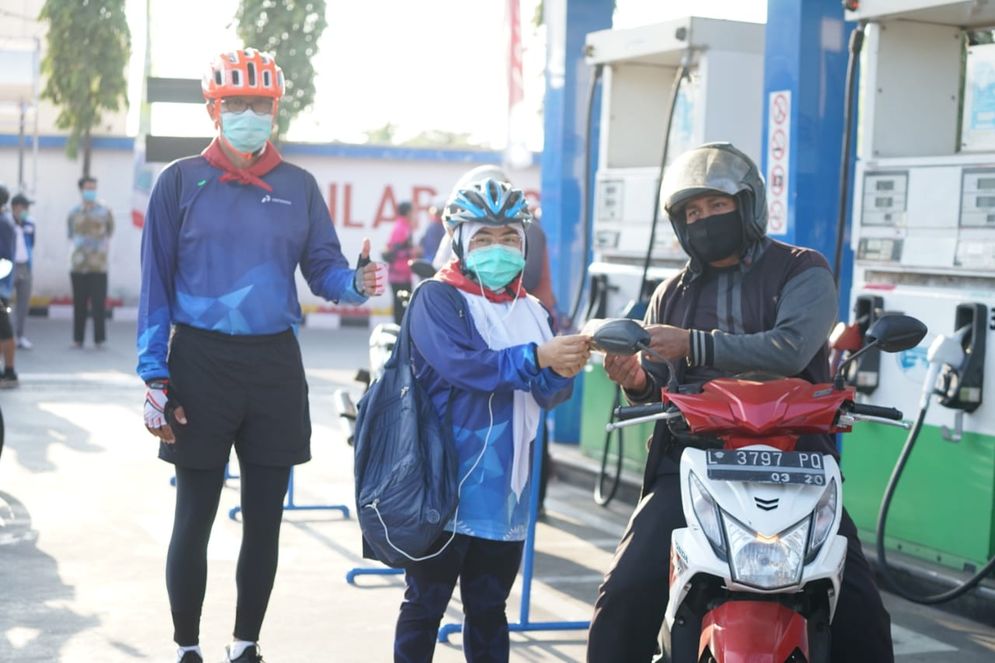 General Manager Pertamina MOR V, C.D. Sasongko (kiri) membagikan masker kepada pelanggan di SPBU di Surabaya. 