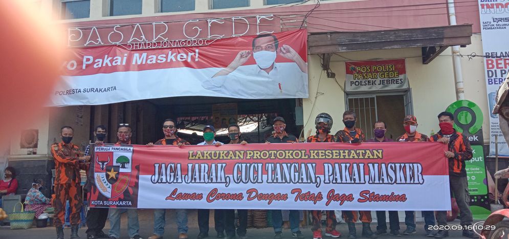 PP memasangan spanduk protokol kesehatan Covid19 di Pasar Gede Solo