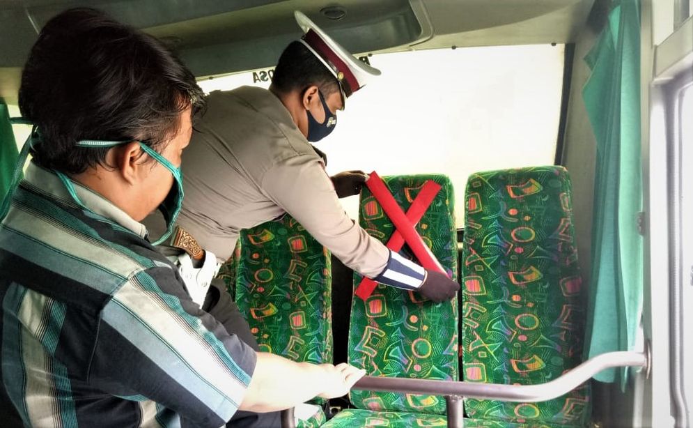 Ilustrasi pihak kepolisian tengah memasang batas duduk berjarak di dalam bus/Foto: ist