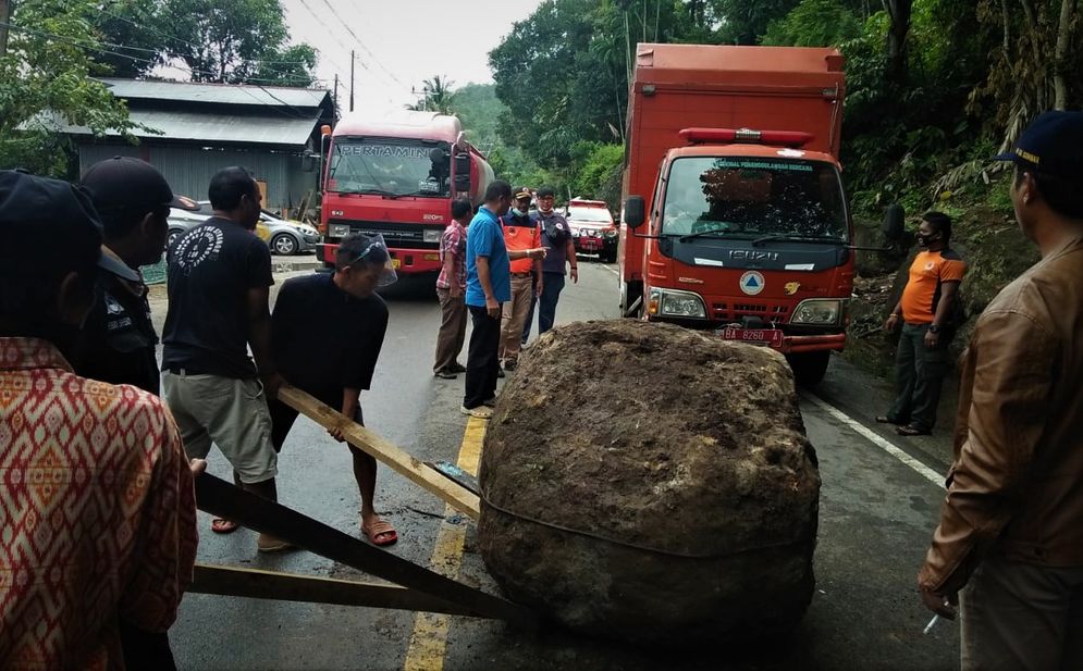 BPBD bersama masyarakat tengah berupaya mengevakuasi batu yang jatuh di badan jalan Padang - Painan/Foto: BPBD