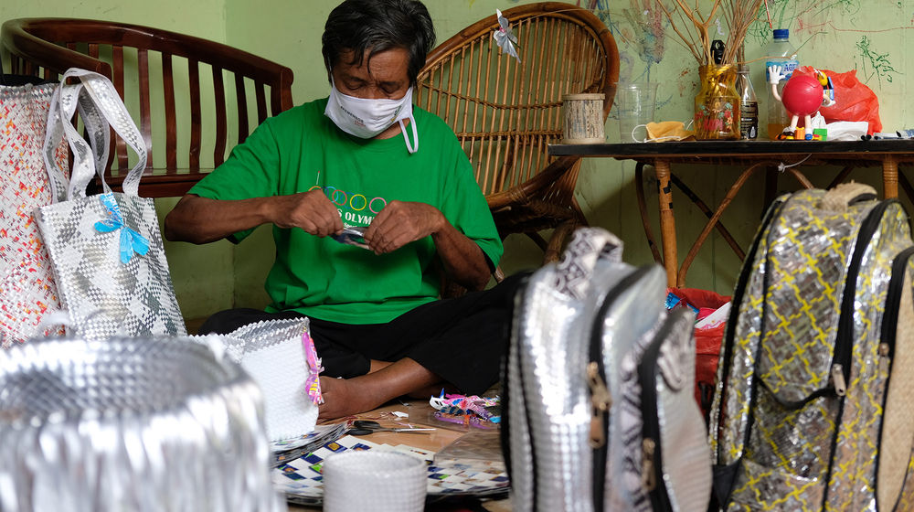 <p>Slamet Riyadi (72) tengah membuat produk kerajinan dari bahan limbah sampah plastik di rumahnya yang dijadikan pondok kreasi lansia bernama Lumintu di Kecamatan Pinang, Tangerang, Banten, Sabtu, 19 September 2020. Nama Lumintu sendiri merupakan singkatan dari “Lumayan Itung-Itung Nunggu Tutup Usia” yang didirikan sejak tahun 1998 ini, sudah ada sekitar 40 lansia yang ikut ambil andil dalam memproduksi kerajinan anyaman dari bahan limbah sampah plastik menjadi keranjang, tikar, tas, dompet, dan aksesoris lainnya yang unik. Produk yang awalnya dijual dengan berkeliling kampung ini kini telah merambah ke pasar nasional bahkan internasional dan diharapkan mampu meningkatkan perekonomian di Indonesia. Foto: Ismail Pohan/TrenAsia</p>
