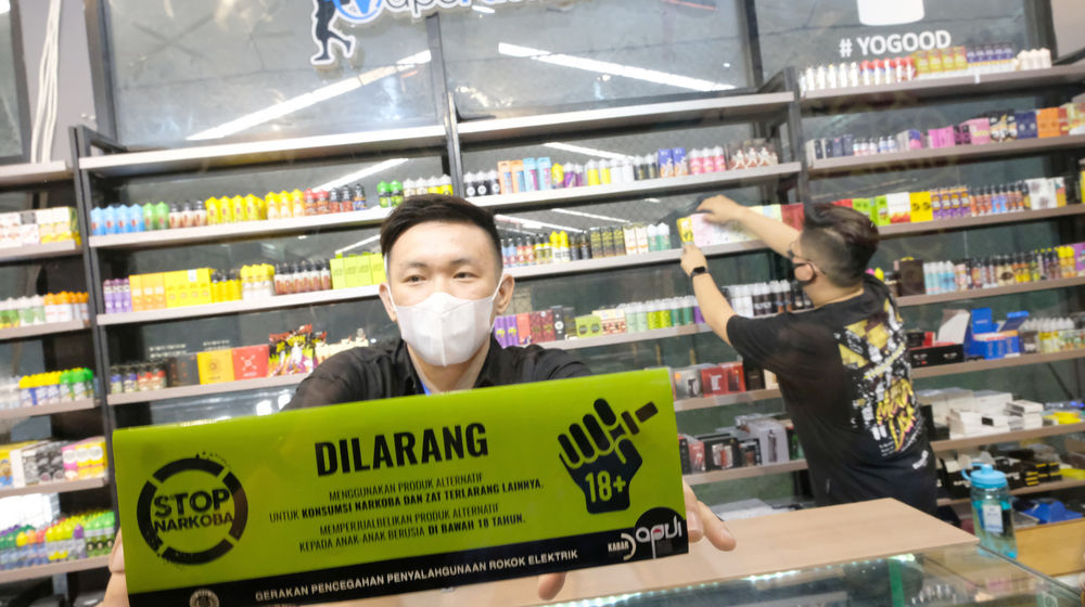 <p>Pemilik toko yang juga Anggota APVI, Rhomedal (kanan) memasang stiker himbauan di toko Vapepackers, Jakarta, Rabu, 9 September 2020. Kegiatan ini merupakan sosialisasi mengenai bahaya penyalahgunaan narkoba pada produk tembakau alternatif atau rokok elektrik melalui gerakan sosial bertajuk “Gerakan Pencegahan Penyalahgunaan Rokok Elektrik (GEPPREK)” yang juga telah dilakukan di Denpasar, Bali, dan Bandung, Jawa Barat. Foto: Ismail Pohan/TrenAsia</p>
