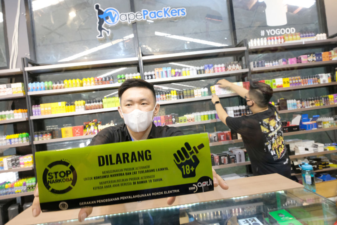 <p>Pemilik toko yang juga Anggota APVI, Rhomedal (kanan) memasang stiker himbauan di toko Vapepackers, Jakarta, Rabu, 9 September 2020. Kegiatan ini merupakan sosialisasi mengenai bahaya penyalahgunaan narkoba pada produk tembakau alternatif atau rokok elektrik melalui gerakan sosial bertajuk “Gerakan Pencegahan Penyalahgunaan Rokok Elektrik (GEPPREK)” yang juga telah dilakukan di Denpasar, Bali, dan Bandung, Jawa Barat. Foto: Ismail Pohan/TrenAsia</p>
