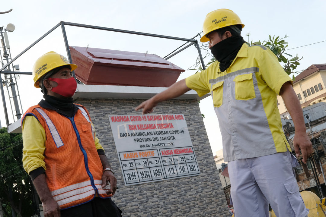 <p>Pekerja berbincang di dekat tugu peti jenazah dan data yang menunjukkan jumlah kasus  COVID-19 di Taman Tongtek, Jatinegara, Jakarta, Selasa, 1 September 2020. Pemprov DKI Jakarta memasang replika peti mati dan papan himbauan waspada COVID-19 di sejumlah lokasi  DKI Jakarta yang masih menjadi wilayah tertinggi penyebaran kasus, dari 2.775 tambahan kasus hari ini, DKI Jakarta menjadi provinsi terbanyak, yakni 901 kasus. Foto: Ismail Pohan/TrenAsia</p>
