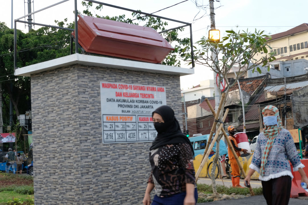 <p>Warga melintas di dekat tugu peti jenazah dan data yang menunjukkan jumlah kasus  COVID-19 di Taman Tongtek, Jatinegara, Jakarta, Selasa, 1 September 2020. Pemprov DKI Jakarta memasang replika peti mati dan papan himbauan waspada COVID-19 di sejumlah lokasi  DKI Jakarta yang masih menjadi wilayah tertinggi penyebaran kasus, dari 2.775 tambahan kasus hari ini, DKI Jakarta menjadi provinsi terbanyak, yakni 901 kasus. Foto: Ismail Pohan/TrenAsia</p>
