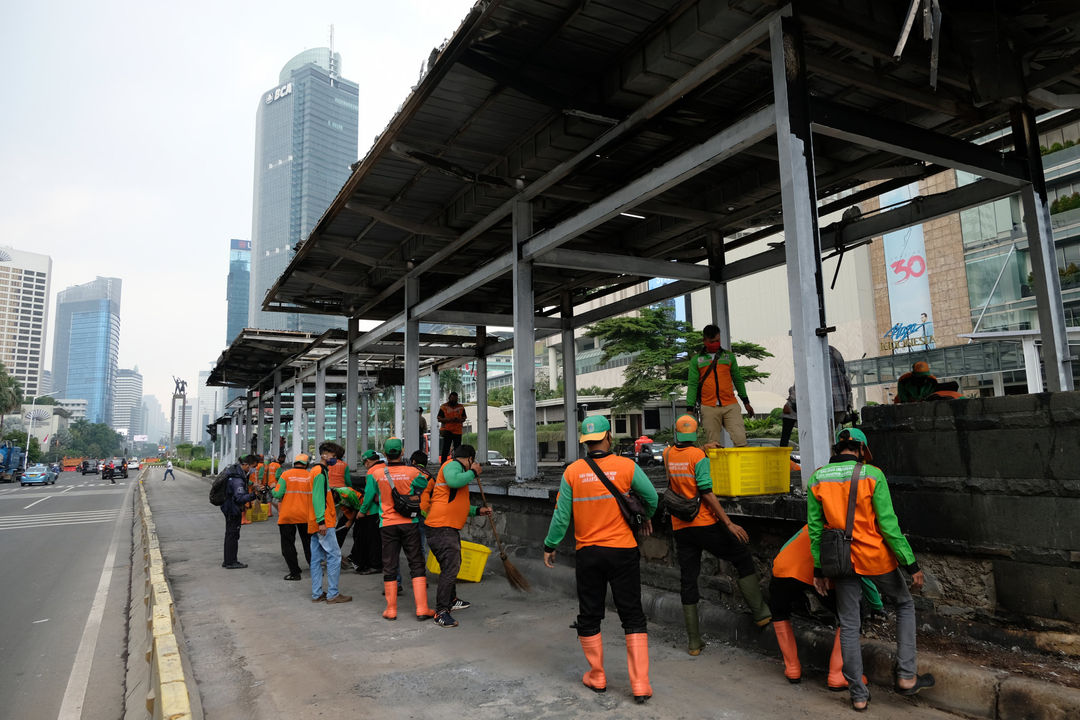 <p>Petugas membersihkan sisa puing di halte Transjakarta yang rusak dan dibakar massa saat aksi unjuk rasa menolak pengesahan UU Cipta Kerja yang berakhir ricuh di kawasan Thamrin, Jumat, 9 Oktober 2020/ Foto: Ismail Pohan/TrenAsia</p>
