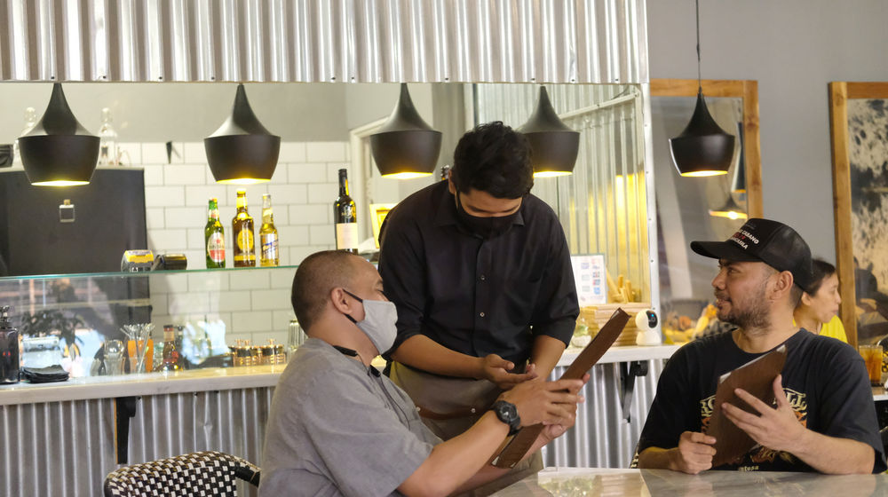 <p>Sejumlah tamu memesan menu makanan di resto COUZ Steak House, Kemang, Jakarta, Selasa, 13 Oktober 2020. Pemprov DKI Jakarta memperbolehkan kembali masyarakat makan di tempat atau dine-in di restoran, rumah makan dan cafe dengan protokol kesehatan khusus diantaranya maksimal 50 persen kapasitas serta jarak antarmeja dan kursi minimal 1,5 meter kecuali untuk pengunjung yang satu domisili. Selain itu, pengunjung dilarang berpindah-pindah atau berlalu-lalang, alat makan dan minum disterilisasi secara rutin, serta pelayan rumah makan atau kafe wajib mengenakan masker, face shield, dan sarung tangan.<br />
Hal itu berlaku selama  PSBB transisi mulai 12 hingga 25 Oktober 2020. Dine-in diperkenankan mulai pukul 6 pagi sampai 9 malam. Layanan take-away dan delivery order tetap beroperasi selama 24 jam. Foto: Ismail Pohan/TrenAsia</p>
