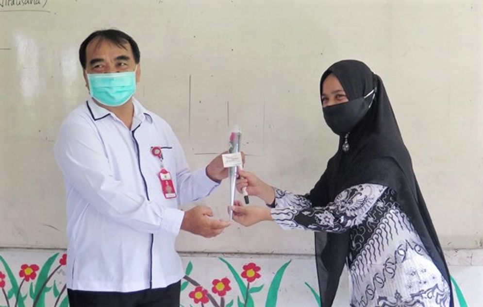 Kepala Dinas Pendidikan Pemuda dan Olahraga (Dikpora), Kanderi menyerahkan setangkai bunga kepada seorang guru di Pariaman. Foto: ist