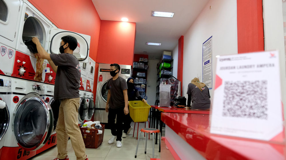 <p>Pekerja memasukkan pakaian kedalam mesin cuci di gerai jasa layanan laundry di kawasan Kemang, Jakarta, Selasa, 24 November 2020. Foto: Ismail Pohan/TrenAsia</p>