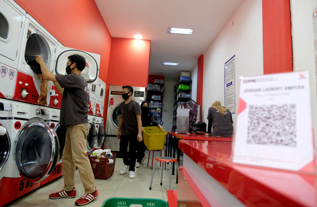 <p>Pekerja memasukkan pakaian kedalam mesin cuci di gerai jasa layanan laundry di kawasan Kemang, Jakarta, Selasa, 24 November 2020. Foto: Ismail Pohan/TrenAsia</p>
