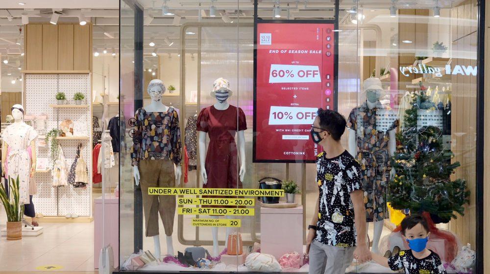 <p>Pengunjung melintas di depan salah satu tenant pusat perbelanjaan yang menggelar diskon belanja Natal dan Tahun Baru di Mal Senayan City, Jakarta, Jum’at, 25 Desember 2020. Foto: Ismail Pohan/TrenAsia</p>