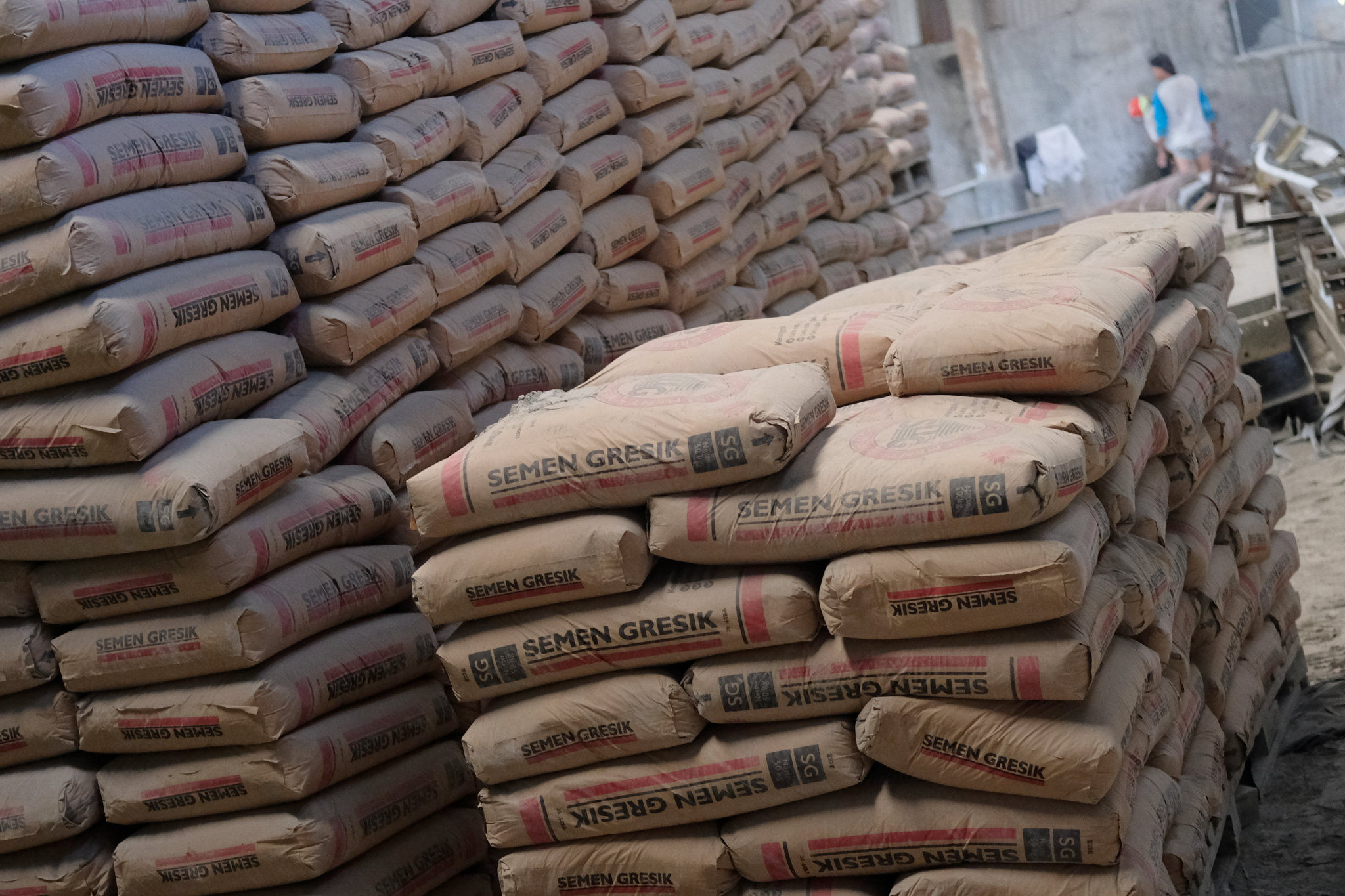 <p>Pekerja berada diantara susunan semen di salah satu gudang distributor semen di Jalan Panjang Arteri Kelapa Dua Raya, Jakarta, Selasa, 1 Desember 2020. Foto: Ismail Pohan/TrenAsia</p>
