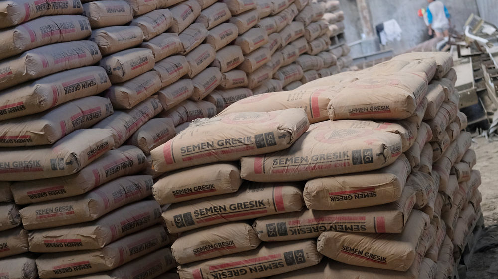 <p>Pekerja berada diantara susunan semen di salah satu gudang distributor semen di Jalan Panjang Arteri Kelapa Dua Raya, Jakarta, Selasa, 1 Desember 2020. Foto: Ismail Pohan/TrenAsia</p>