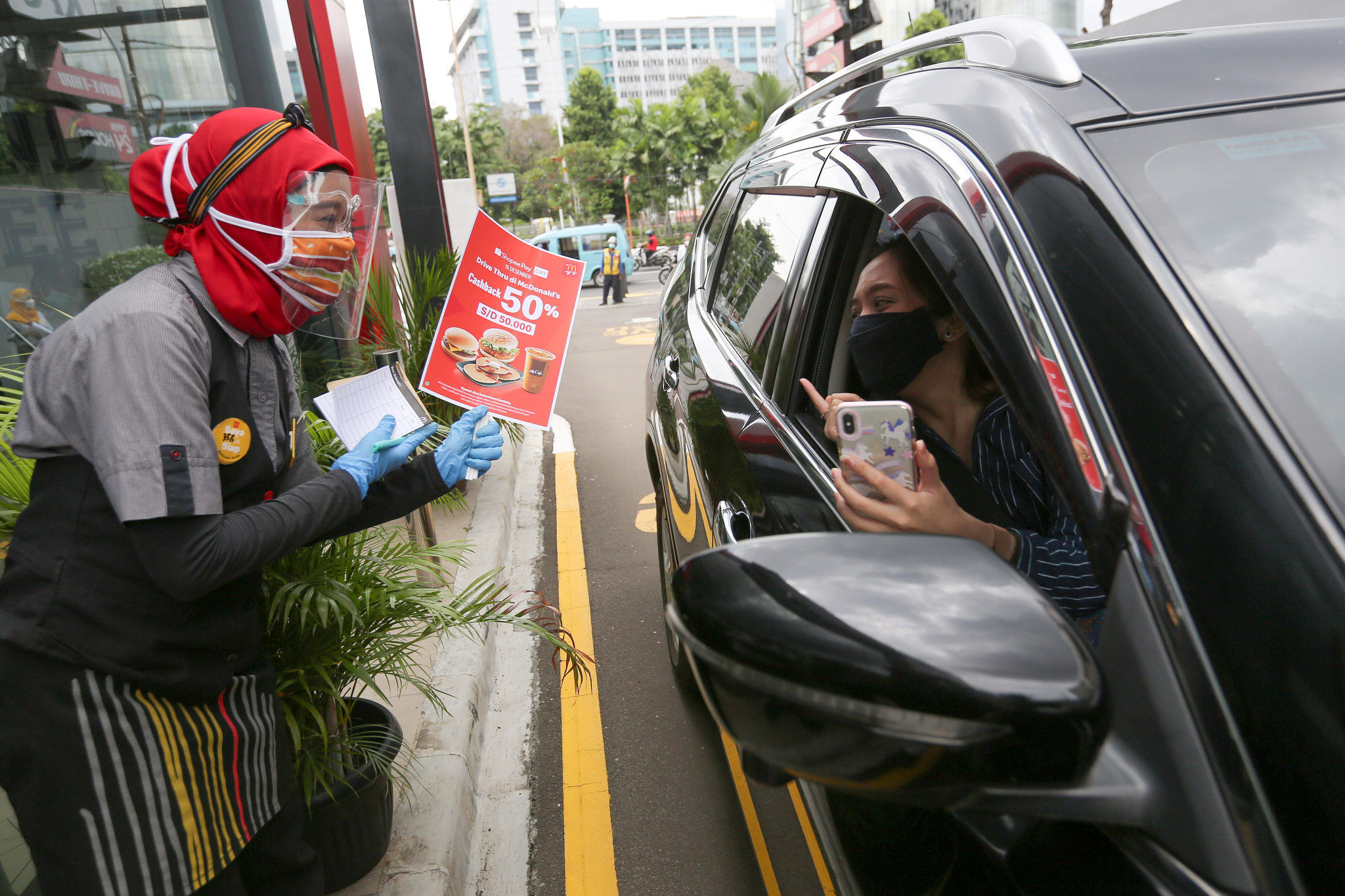 <p>Pramusaji menunjukkan brosur promo 50% Cashback ShopeePay Day kepada pengunjung di Drive Thru McDonald&#8217;s Salemba, Jakarta Pusat, Jum&#8217;at, 18 Desember 2020. Foto: Ismail Pohan/TrenAsia</p>
