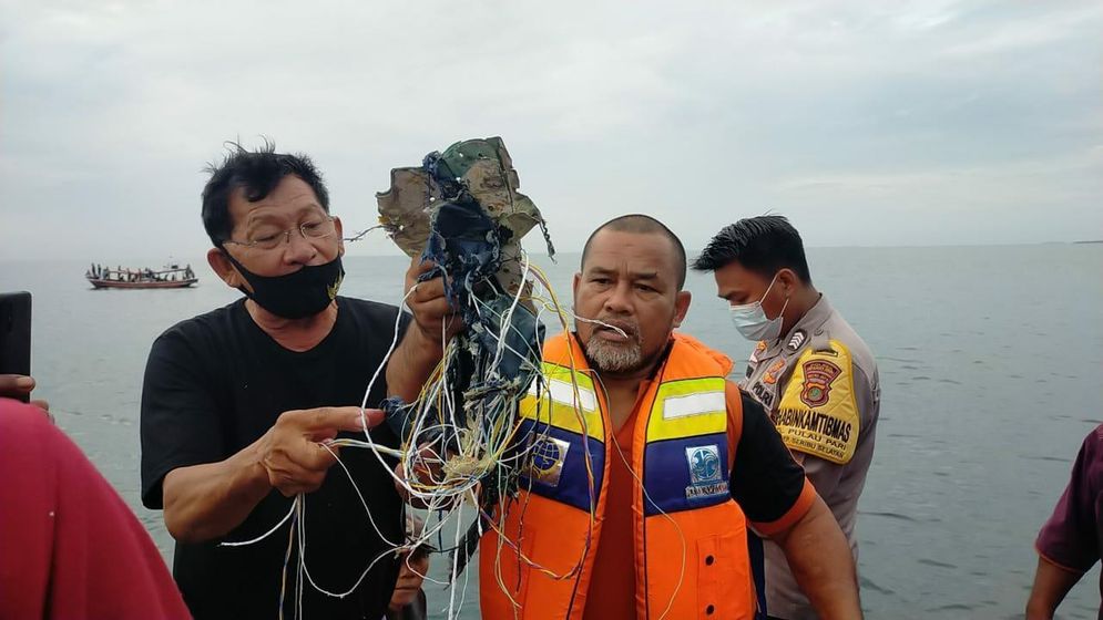 Petugas menunjukan serpihan yang diperkirakan bagian dari pesawat yang hilang