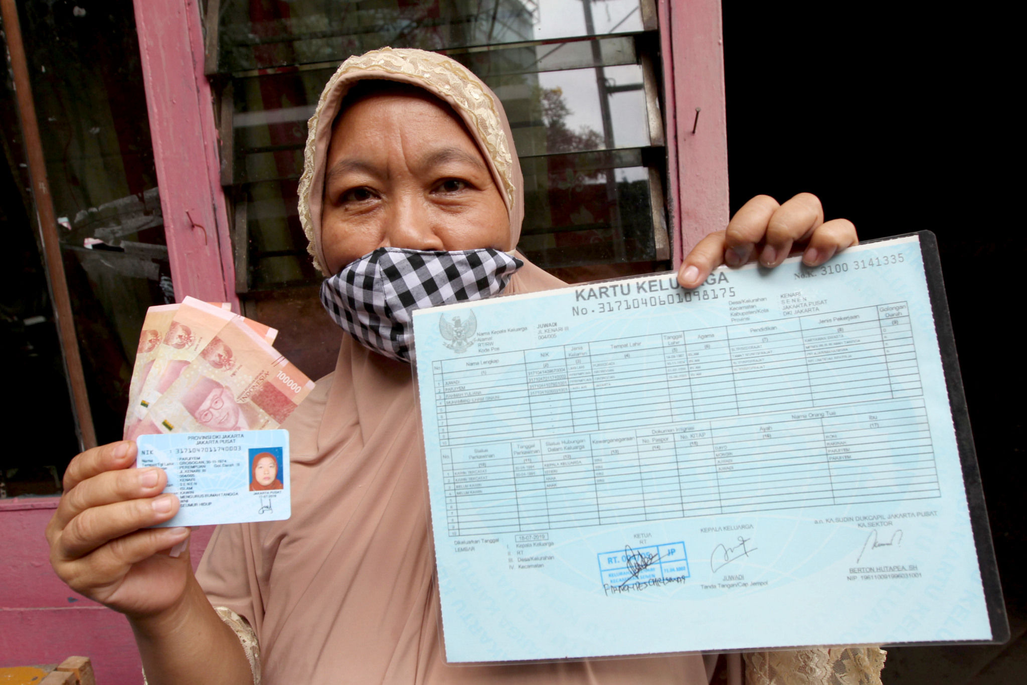 <p>Warga RW 05 penerima Bantuan Sosial Tunai (BST) menunjukkan dokumen persyaratan dan uang yang telah diterima di kawasan Kelurahan Kenari, Senen, Jakarta, Rabu, 6 Januari 2021. Foto: Ismail Pohan/TrenAsia</p>
