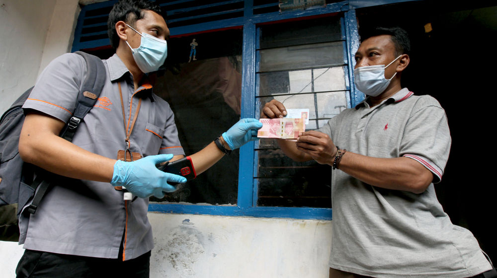 <p>Petugas menyerahkan uang kepada warga RW 05 penerima Bantuan Sosial Tunai (BST) di kawasan Kelurahan Kenari, Senen, Jakarta, Rabu, 6 Januari 2021. Foto: Ismail Pohan/TrenAsia</p>
