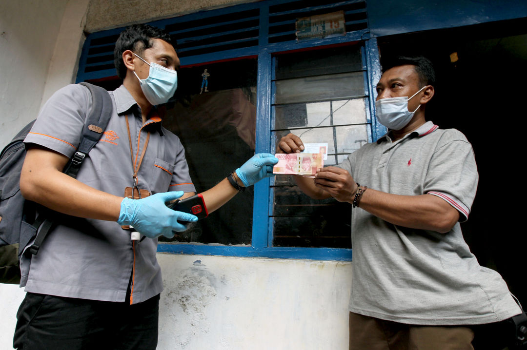 <p>Petugas menyerahkan uang kepada warga RW 05 penerima Bantuan Sosial Tunai (BST) di kawasan Kelurahan Kenari, Senen, Jakarta, Rabu, 6 Januari 2021. Foto: Ismail Pohan/TrenAsia</p>
