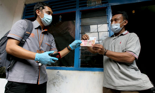 <p>Petugas menyerahkan uang kepada warga RW 05 penerima Bantuan Sosial Tunai (BST) di kawasan Kelurahan Kenari, Senen, Jakarta, Rabu, 6 Januari 2021. Foto: Ismail Pohan/TrenAsia</p>
