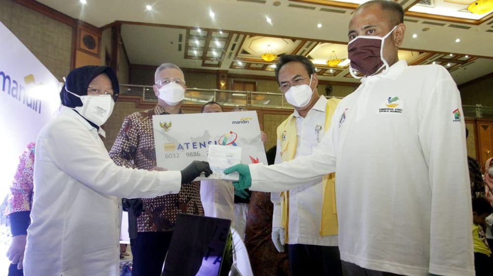 <p>Menteri Sosial (Mensos) Tri Rismaharini (kiri) menyerahkan dokumen dan mock up kartu peserta program ATENSI kepada seorang penerima didampingi Dirjen Rehabilitasi Sosial Kemensos R Harry Hikmat (dua kanan) dan Direktur Hubungan Kelembagaan Bank Mandiri Rohan Hafas di Jakarta. Rabu, 13 Januari 2021 / Perseroan</p>
