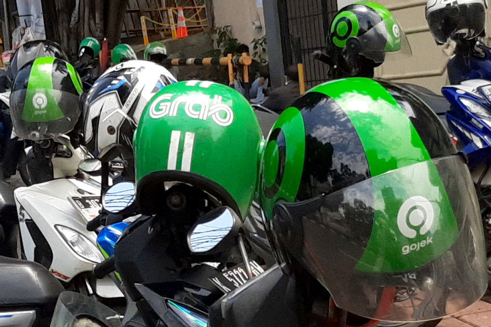 Atribut helm pengemudi ojek daring GrabBike dan Gojek tampak di atas motor yang terparkir di kawasan Gandaria, Jakarta, Selasa, 22 September 2020.