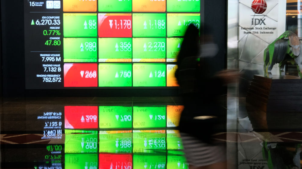 <p>Karyawan melintas dengan latar layar pergerakan indeks harga saham gabungan (IHSG) di gedung Bursa Efek Indonesia (BEI), Jakarta, Senin, 15 Februari 2021. Foto: Ismail Pohan/TrenAsia</p>
