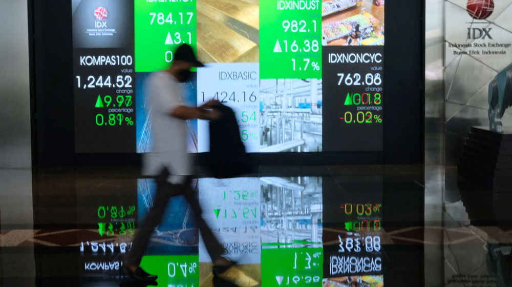 <p>Karyawan melintas dengan latar layar pergerakan indeks harga saham gabungan (IHSG) di gedung Bursa Efek Indonesia (BEI), Jakarta, Senin, 15 Februari 2021. Foto: Ismail Pohan/TrenAsia</p>