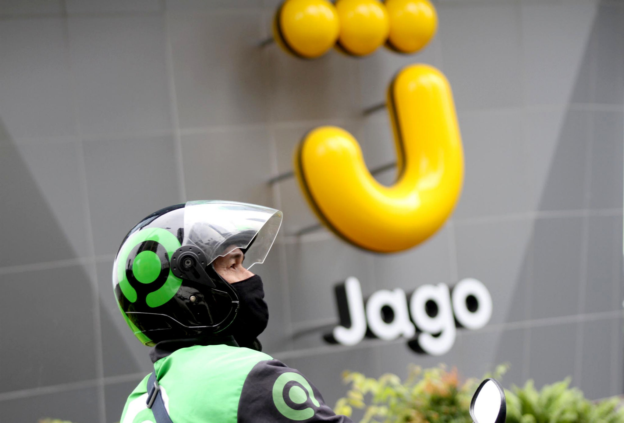 <p>Mitra Driver Gojek menunggu customer di dekat logo Bank Jago di kawasan Mega Kuningan, Jakarta, Selasa, 16 Februari 2021. Foto: Panji Asmoro/TrenAsia</p>
