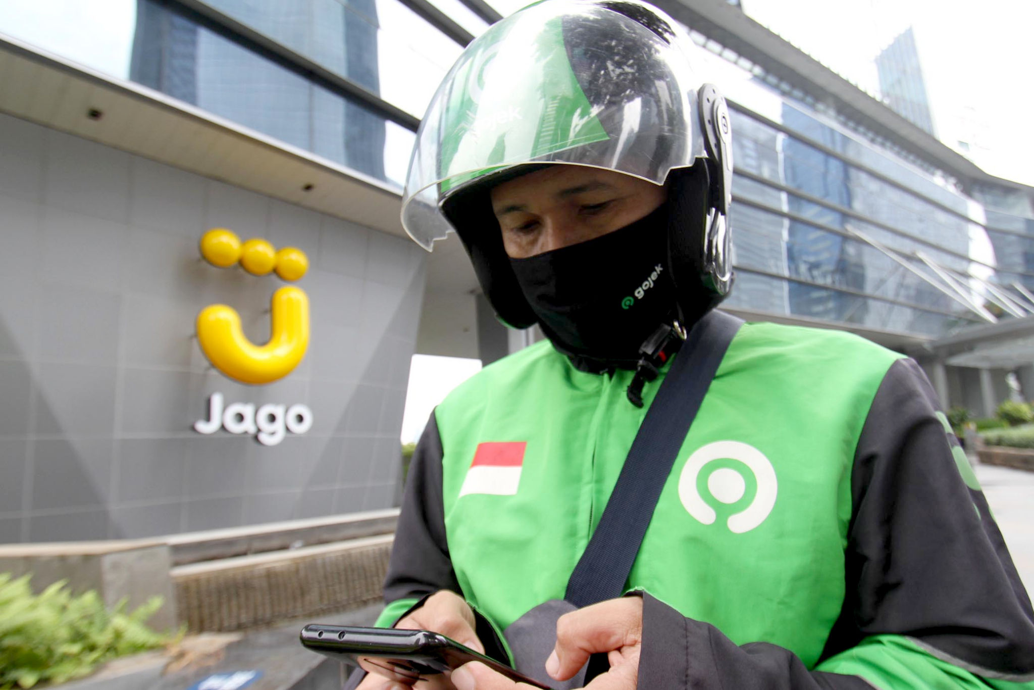 <p>Mitra Driver Gojek menunggu customer di dekat logo Bank Jago di kawasan Mega Kuningan, Jakarta, Selasa, 16 Februari 2021. Foto: Panji Asmoro/TrenAsia</p>
